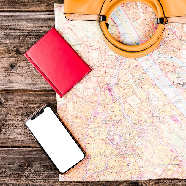 Vista elevata della borsetta, mappa, diario e smartphone su fondo di legno