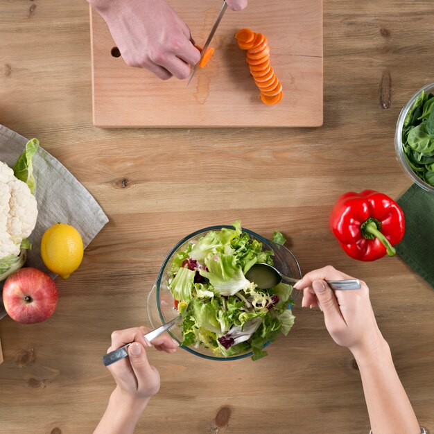 Vista elevata della mano della gente che prepara cibo sul bancone della cucina in legno