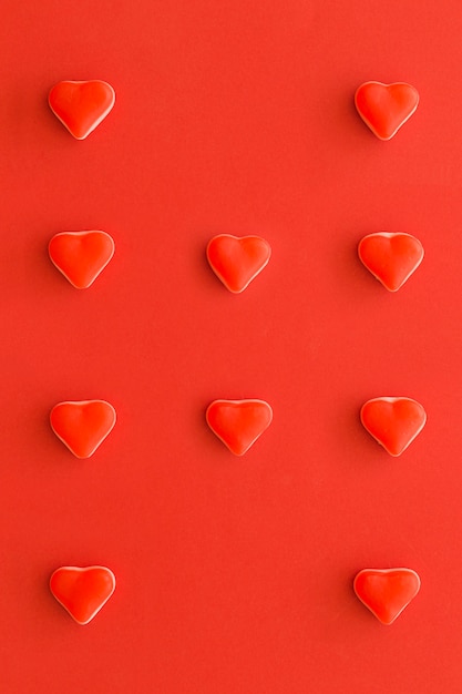 Vista elevata delle caramelle di forma del cuore in una fila sul contesto rosso