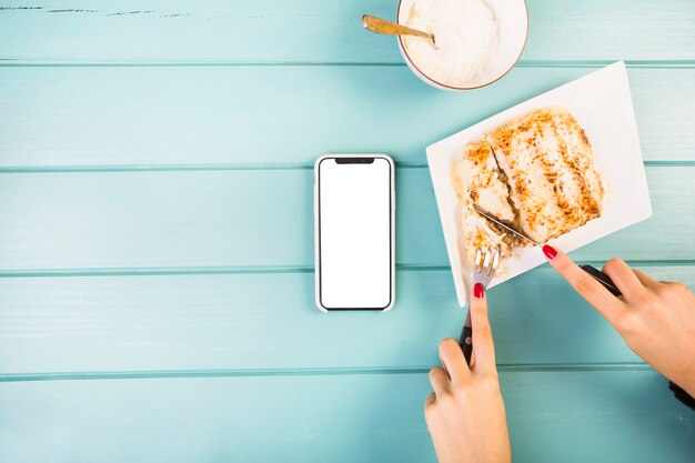 Vista elevata delle lasagne di taglio della mano della donna