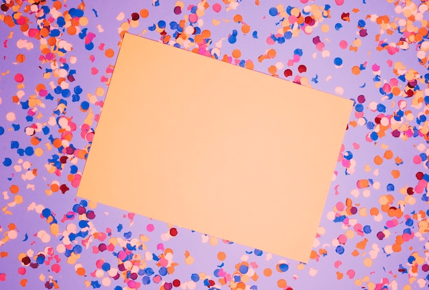 Vista elevata di carta bianca sopra coriandoli colorati su sfondo viola
