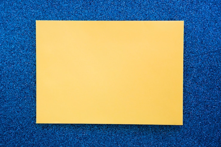 Foto gratuito vista elevata di carta cartone giallo su sfondo blu