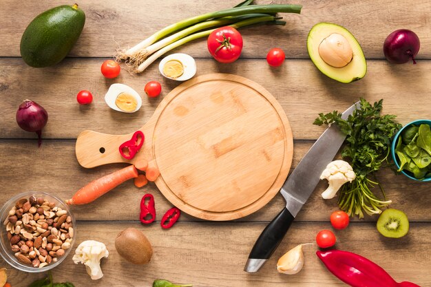 Vista elevata di ingredienti freschi; uovo; verdure e tagliere con coltello sul tavolo