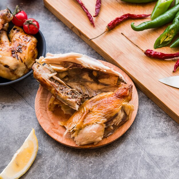 Vista elevata di pollo arrostito mezzo mangiato con peperoncini rossi e verdi