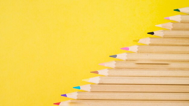 Vista elevata di varie matite colorate su sfondo giallo