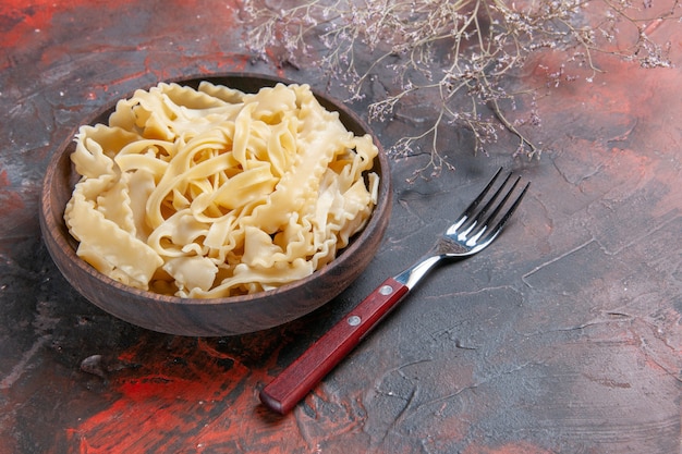 Vista frontale a fette di pasta cruda all'interno del piatto sulla superficie scura pasta scura pasta cibo crudo