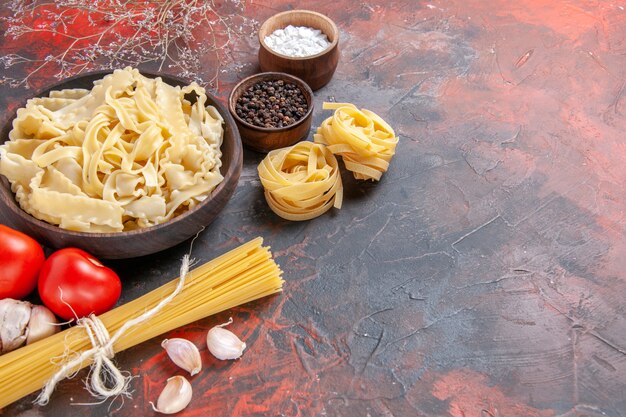 Vista frontale a fette di pasta cruda con condimenti sulla superficie scura pasta pasta cibo scuro