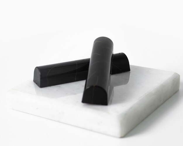 Vista frontale a forma di piastrella nera con pietre di cioccolato progettata sulla scrivania bianca