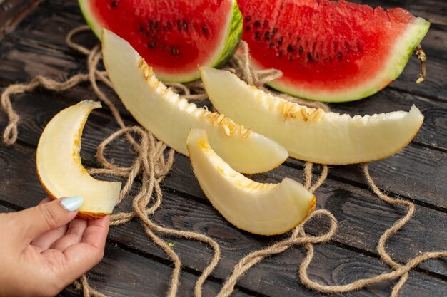 Vista frontale affettata di anguria fresca tagliata a metà frutta dolce con melone sullo sfondo rustico