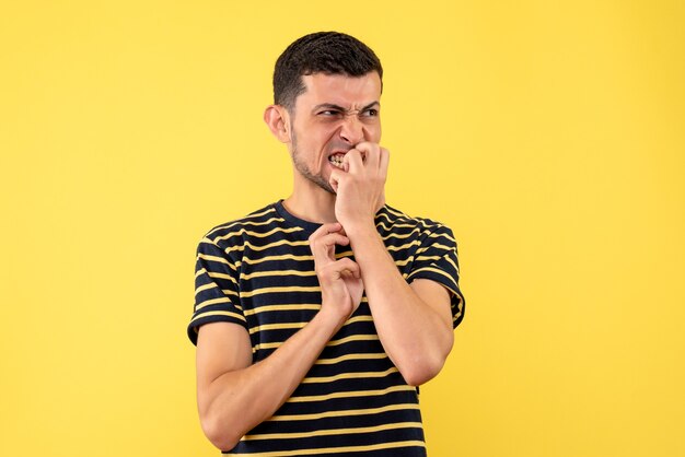 Vista frontale agitato giovane uomo in bianco e nero a strisce t-shirt sfondo giallo isolato