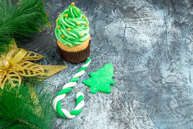 Vista frontale albero di natale cupcake natale caramelle ornamenti di natale su sfondo grigio con copia spazio