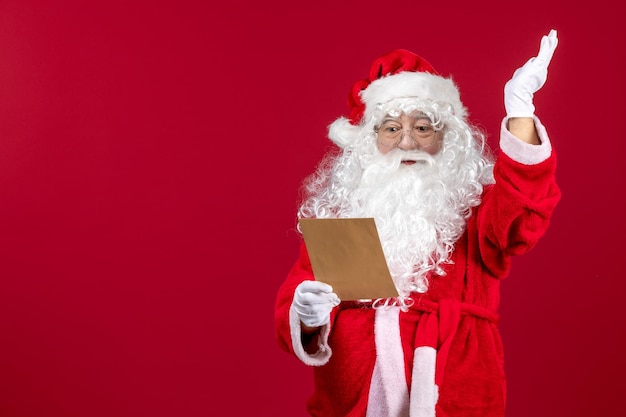 Vista frontale babbo natale che legge la lettera del bambino sull'emozione delle vacanze di natale presente rosso