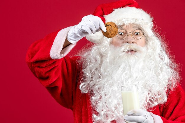 Vista frontale babbo natale che mangia biscotti e beve latte