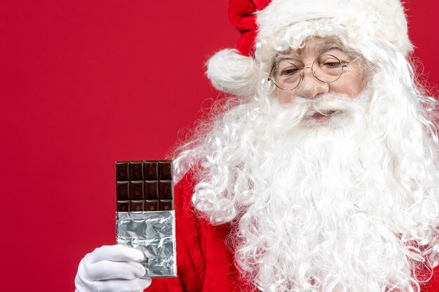 Vista frontale babbo natale che tiene la barretta di cioccolato