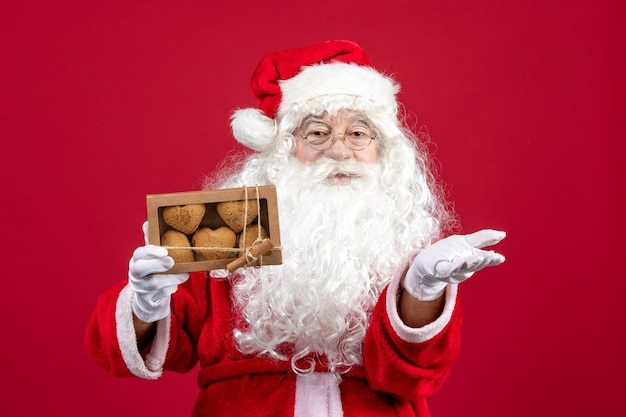 Vista frontale babbo natale che tiene pacchetto con biscotti