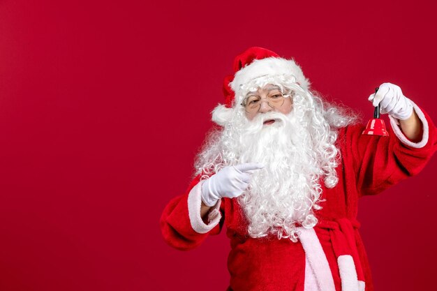 Vista frontale babbo natale che tiene un campanello sull'emozione rossa festa del regalo di capodanno di natale