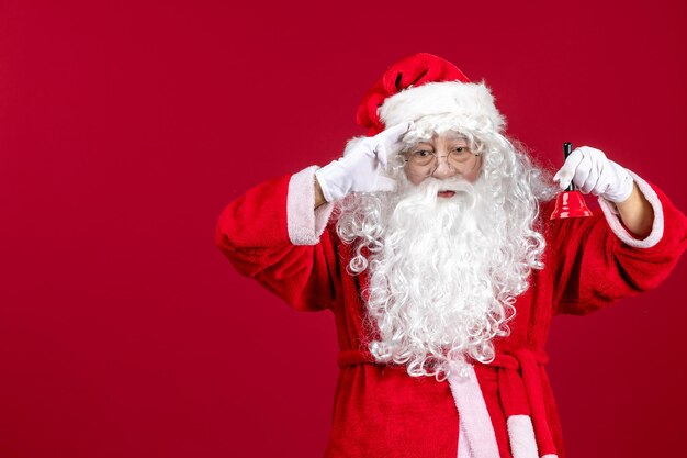 Vista frontale babbo natale che tiene una campanella durante le vacanze di emozione di capodanno di natale rosso