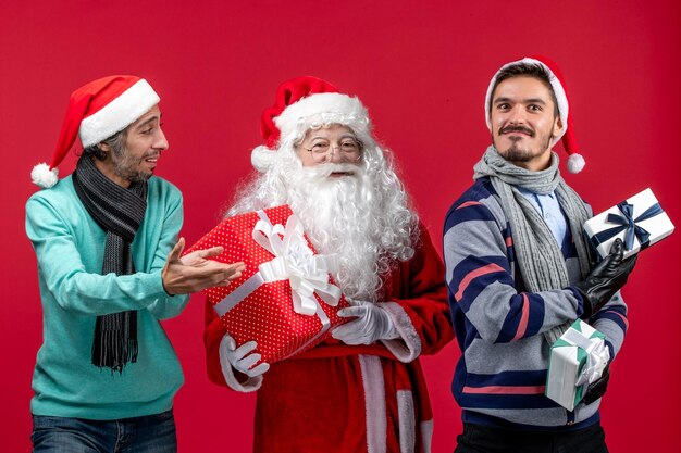 Vista frontale babbo natale con due maschi che tengono regali sull'emozione del regalo di capodanno rosso rosso natale