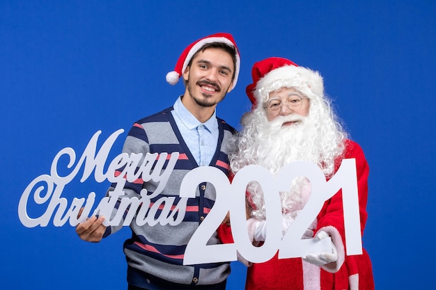 Vista frontale babbo natale con giovane azienda maschio e scritti di buon natale su regalo blu