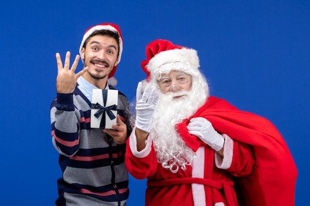 Vista frontale babbo natale con giovane borsa da trasporto maschio piena di regali su emozioni blu vacanza natale presente