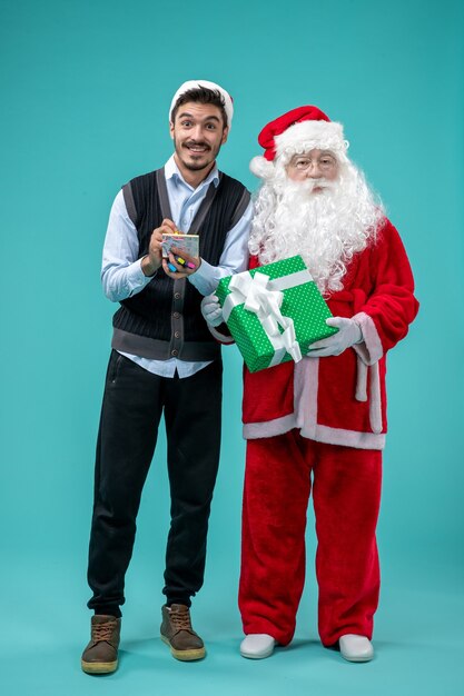 Vista frontale Babbo Natale con il giovane maschio che sta prendendo appunti sullo sfondo blu