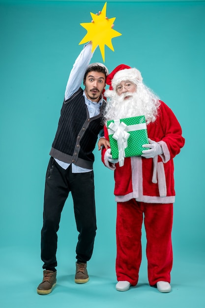 Vista frontale Babbo Natale con il giovane maschio che sta tenendo il cartello giallo su sfondo blu