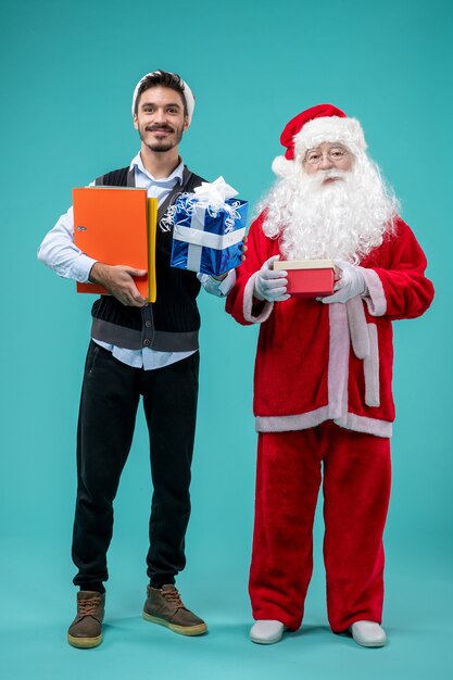 Vista frontale Babbo Natale con il giovane maschio e regali sul pavimento blu neve Capodanno vacanza vacanze Natale