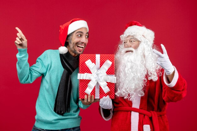 Vista frontale babbo natale con maschio che tiene festa presente su regalo rosso emozione rosso natale capodanno