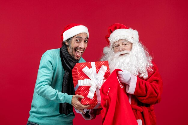 Vista frontale babbo natale con maschio che tira fuori il regalo dalla borsa in vacanza rossa emozione di natale