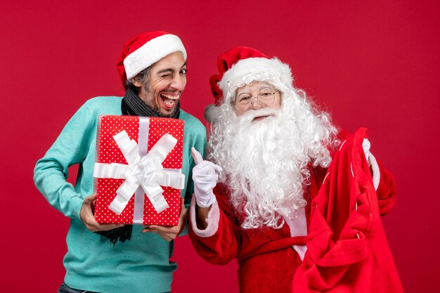 Vista frontale babbo natale con maschio che tira fuori il regalo dalla borsa sulle emozioni di natale rosso colore rosso