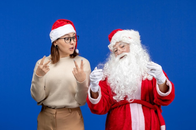 Vista frontale babbo natale con una bella femmina in piedi sull'emozione di natale della neve di colore blu