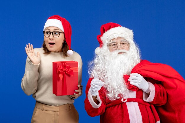 Vista frontale babbo natale con una giovane donna che tiene presente sul colore blu dell'emozione delle vacanze