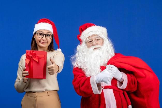 Vista frontale babbo natale con una giovane donna che tiene presente sulla scrivania blu vacanza neve emozione