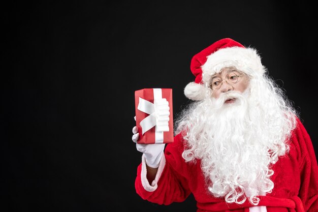 Vista frontale babbo natale in abito rosso classico che tiene presente