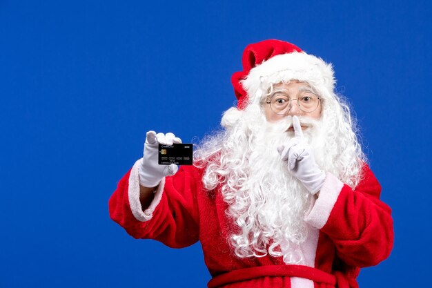 Vista frontale babbo natale in abito rosso con carta di credito nera su regali di vacanza blu colore di natale