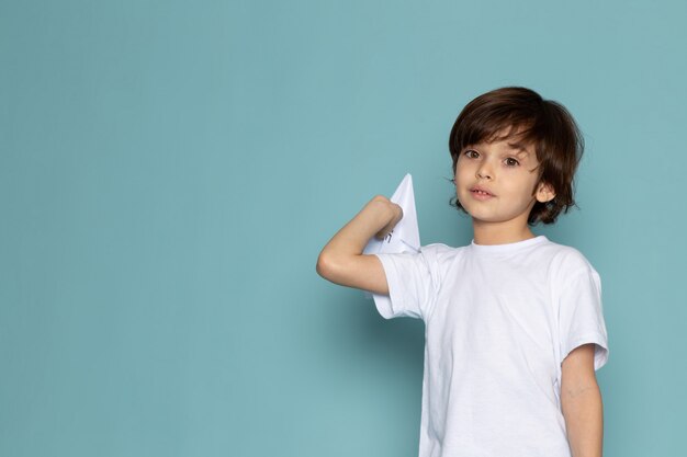 vista frontale bambino carino adorabile dolce azienda aereo di carta sulla scrivania blu