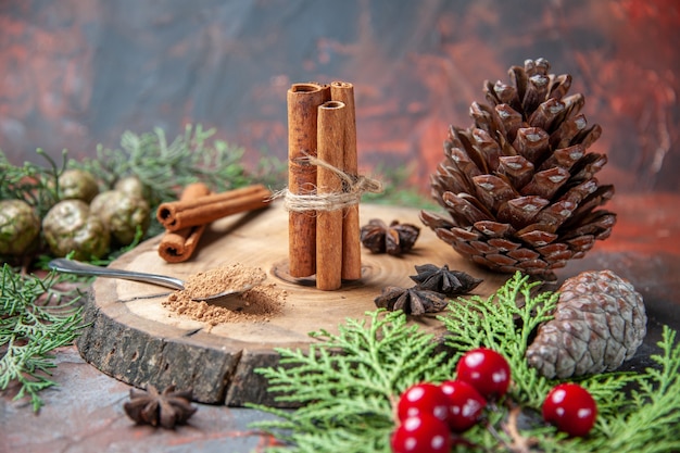 Vista frontale bastoncini di cannella su tavola di legno polvere di cannella pigne anice al buio