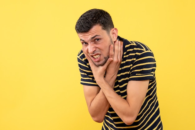 Vista frontale bel maschio in t-shirt a righe bianco e nero che tiene la gola su sfondo giallo isolato