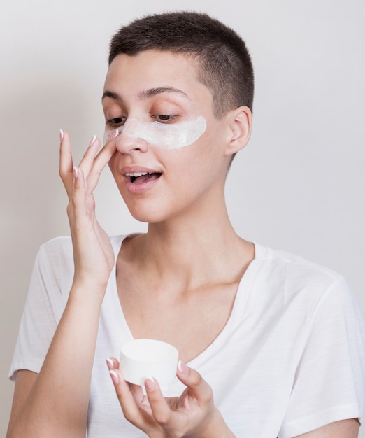 Vista frontale bella donna con i capelli corti con una crema per la pelle