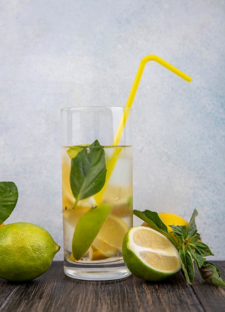Vista frontale bicchiere d'acqua con spicchi di limone menta giallo paglierino e lime