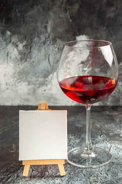 Vista frontale bicchiere di vino tela bianca su cavalletto in legno su oscurità