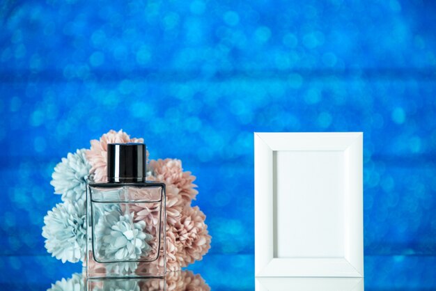 Vista frontale bottiglia di profumo piccola cornice bianca fiori su sfondo blu sfocato con spazio libero