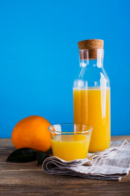 Vista frontale bottiglia e bicchiere di succo d'arancia