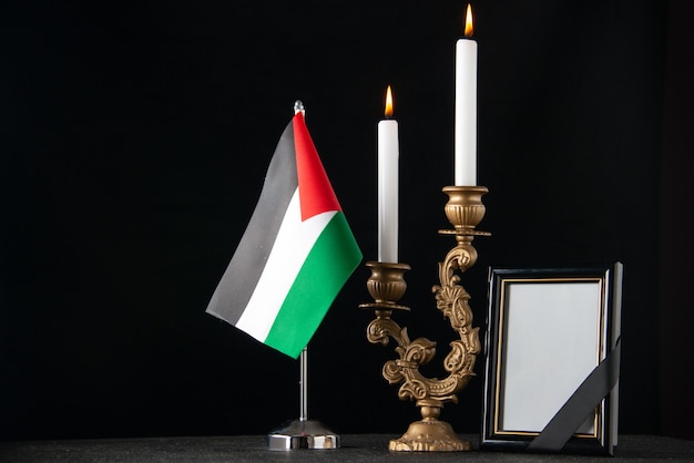 Vista frontale candele accese con bandiera palestinese e superficie scura cornice immagine