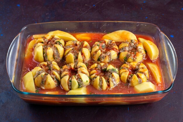 Vista frontale carne macinata all'interno di patate cotte un delizioso pasto sulla scrivania viola scuro.