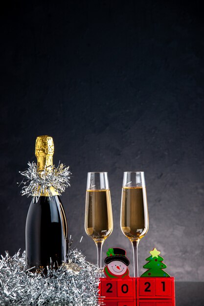 Vista frontale champagne in bottiglia e bicchieri blocchi di legno su superficie scura