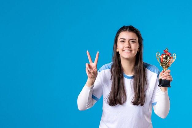 Vista frontale che posa giocatore femminile con la tazza sull'azzurro