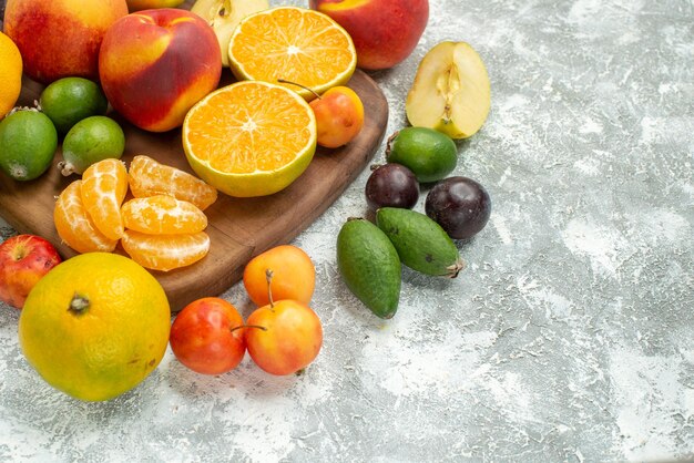 Vista frontale composizione di frutta diversa affettata e frutta fresca intera su spazio bianco