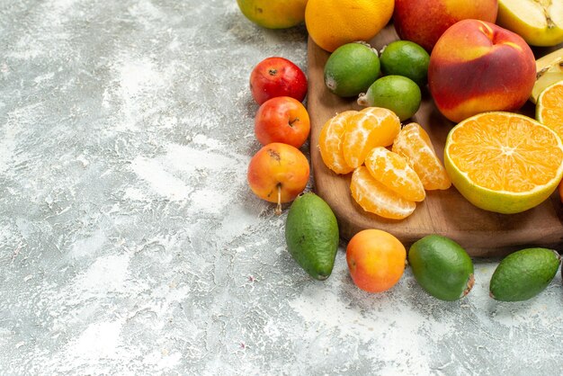 Vista frontale composizione di frutta diversa affettata e frutta fresca intera su spazio bianco