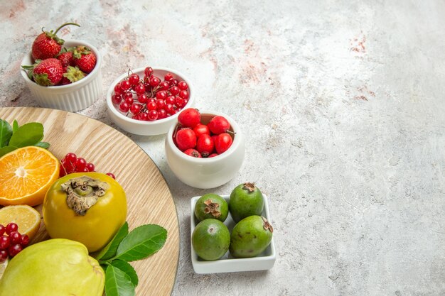 Vista frontale composizione di frutta frutti diversi su tavola bianca frutti di bosco freschi maturi